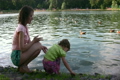 mother with girl and ducks on pond