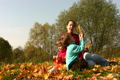 mother with children sit in autumn leaves