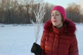 portrait of woman blows to branchlet covered with hoarfrost