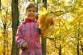 girl waving hand with leaves in park