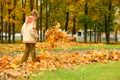 boy walking through fall leaves on ground in park