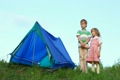 boy and little girl having joines hands stands near tent